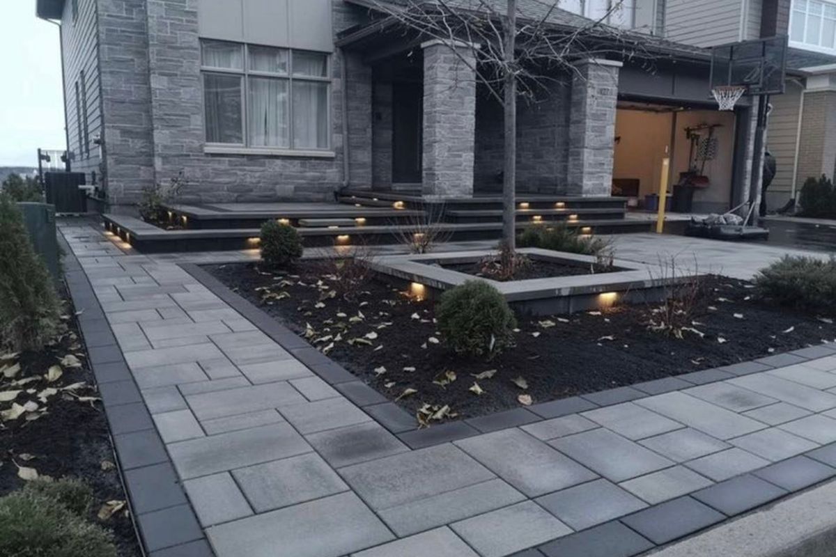 Interlocking courtyard with charcoal border, garden beds and low landscape lighting