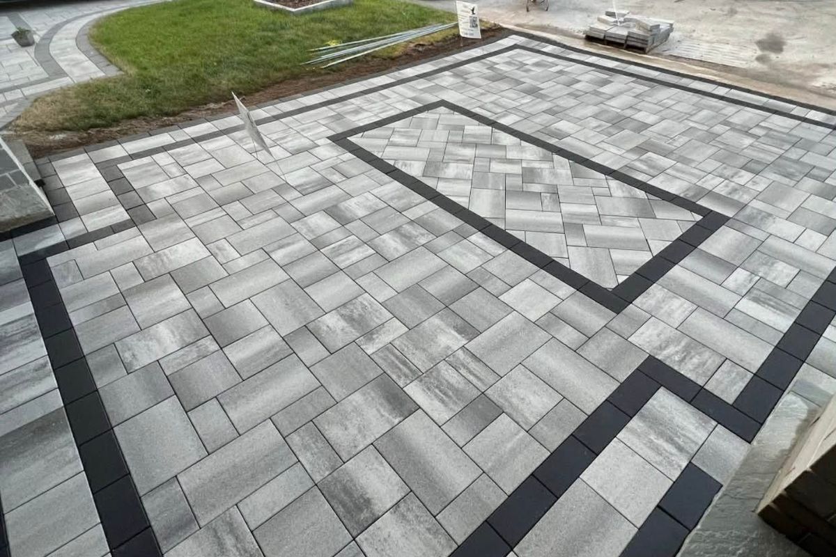 Large paver patio with a dark inlaid border running through the centre