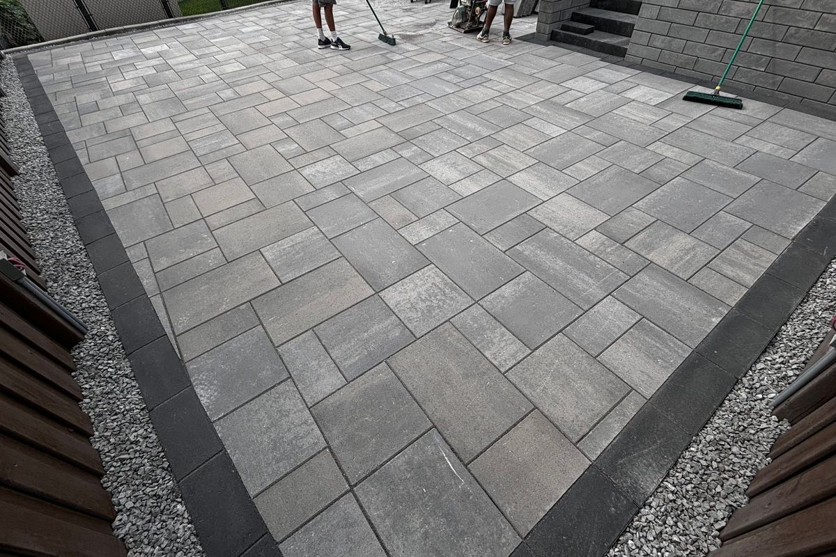 Paver patio framed by a charcoal border and a gravel edge