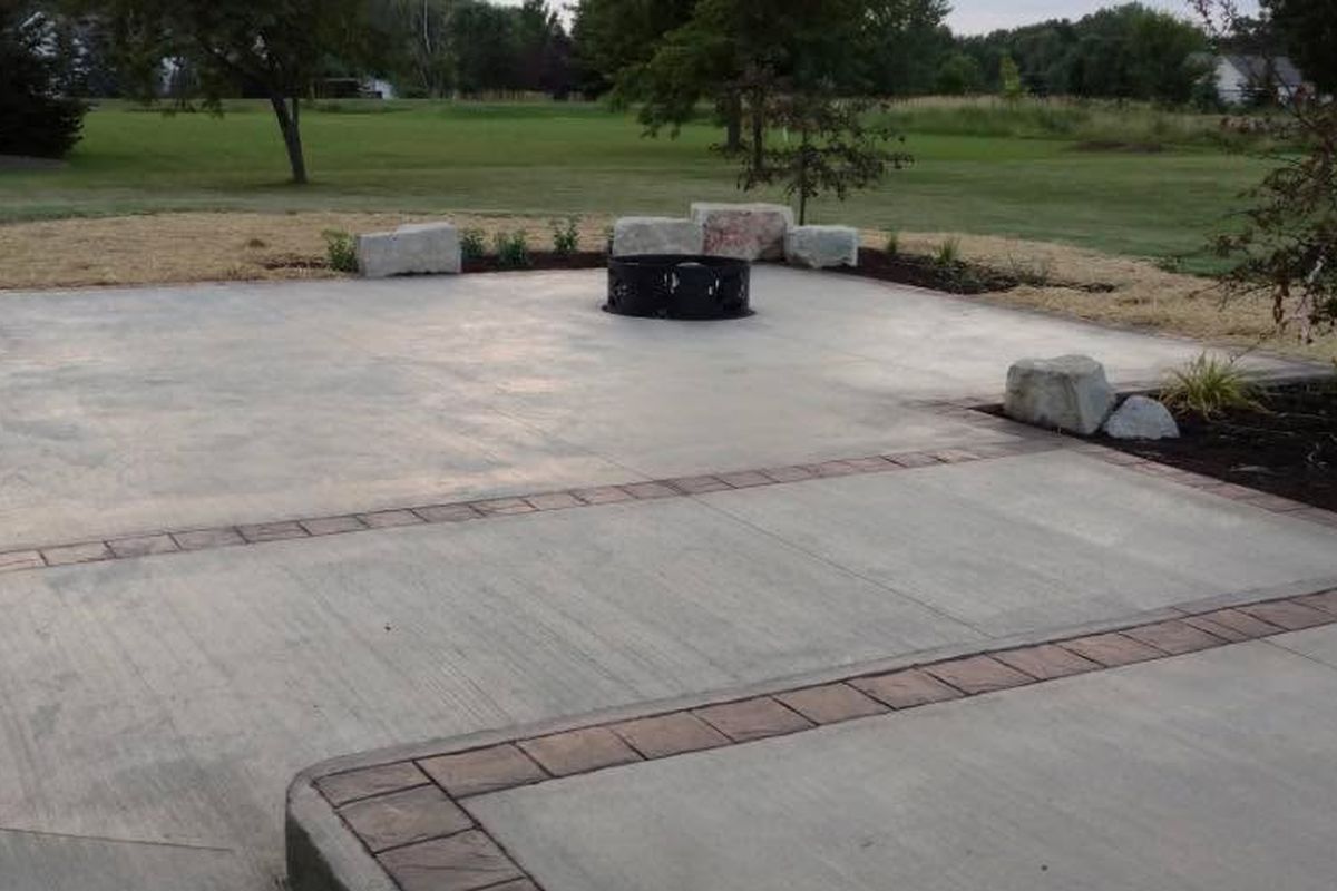 Wide concrete driveway and pad with a contrasting border and a fire pit