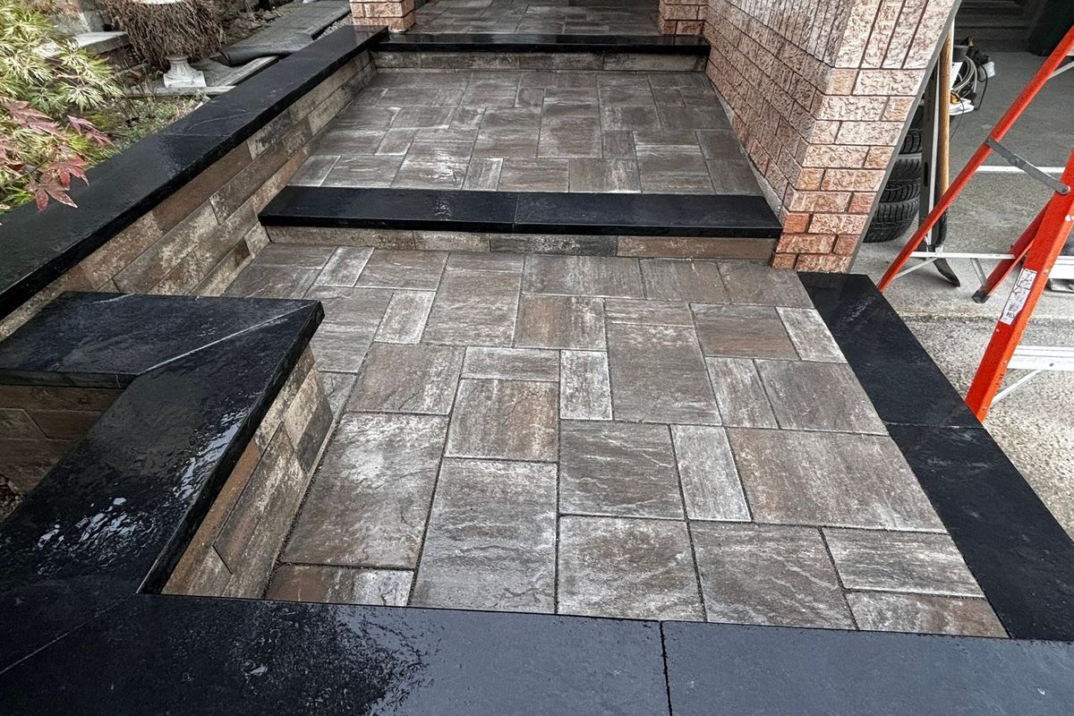 Paver walkway with a charcoal border running between brick pillars